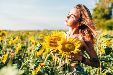 A young topless girl stands in sunflowers