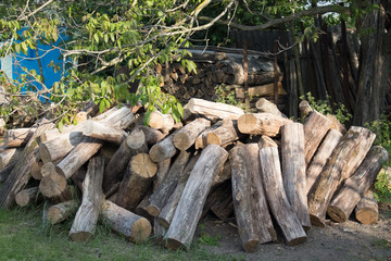 Pile of logs close-up in the countryside. Harvesting firewood for the winter for the bath. Dry round logs with cracks