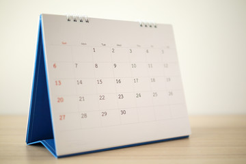 Calendar page close up on wood table with white wall background