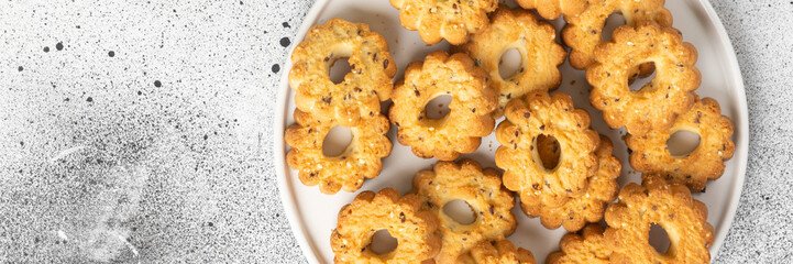 Shortbread in a large white ceramic plate on the light gray kitchen table. There are a lot of cookies in the plate. Homemade delicious pastries. Top view with a space for text. Banner