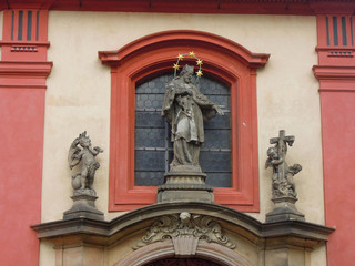 Fototapeta na wymiar Statue of Czech saint John of Nepomuk, decorating St. George's Basilica, Prague, Czech Republic. Building is most oldest surviving church withing Prague Castle. Church is also serves as concert hall
