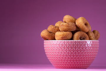 Cinnamon Sugar Mini Donuts in a bowl on a pink background with copy space
