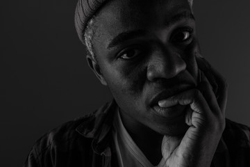 Closeup portrait of a black African man with big lips biting his finger in black and white light