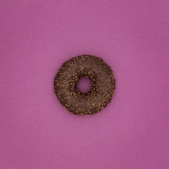 Delicious donut with icing and candy on a pink background.