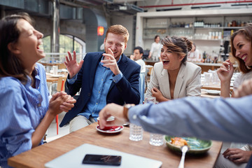 group of young  people laughing at lunch, friends, colleagues, business partners concept