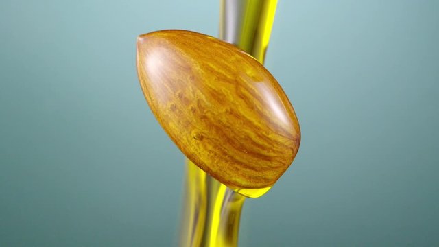 Almond covered with oil on green background. Almond oil pouring. Slow motion, 4K 