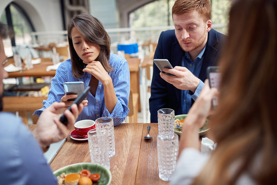 people at lunch occupied with their mobile phones. not present, social issues, victims of modern technology concept