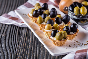 delicious snack tartlets on rustic wooden background