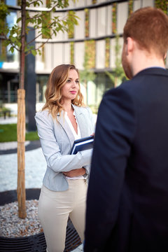 young caucasian businesswoman looking curiously  her interlocutor outdoor in front of business building. outdoor, unofficial, meeting, chat