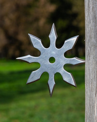 Shuriken (throwing star), traditional japanese ninja cold weapon stuck in wooden background