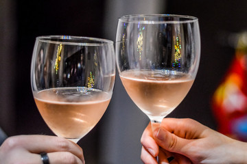 Hands and glasses of toasting friends with rose champagne close up