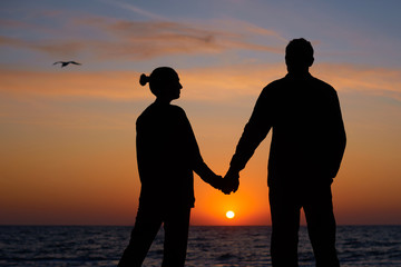 two people in love at sunset. silhouette of man and woman dreaming on beach
