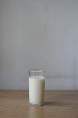 a glass of milk on a wooden table with a gray background