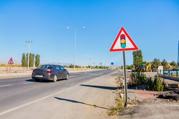 International warning traffic sign 'Traffic light regulation'. Some cars moving on highway