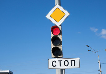 International road sign 'Main road', LED traffic light (shows the prohibiting red light), & sign with writing 'Stop' (written in Russian)