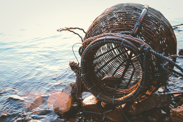Woven rattan creel or fishing basket that is a traditional fish container in rural fishing village in Cambodia that shows authentic khmer daily life and local culture - obrazy, fototapety, plakaty