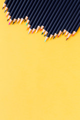Vertical photo. Color pencils on a yellow background. Free space for text. Business concept. Back...
