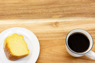 Piece of cake and black coffee on wooden table in cafe ,top view.
