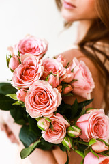 Close up of a pink roses bouquet in woman's arms. No face, close up.