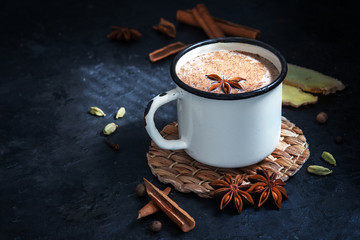 Masala tea with cinnamon and anise on a blue concrete table. A white cup of masala tea with spices on a concrete table.