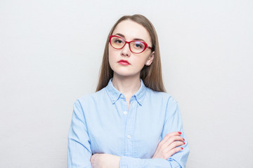 Nerd girl in red glasses looks thoughtfully at the camera, portrait, white background