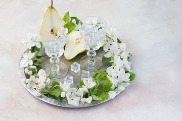cut pears, glasses, ice, and pear flowers on a light background 