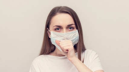 Girl in a medical mask is ill, girl coughing, white background, copy space, 16:9
