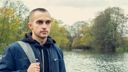 Concept of tourism. Person travels the world, guy with backpack looks at the beautiful landscape, portrait, toned, 16:9