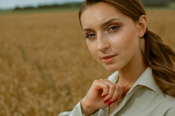 Portrait of a lovely pleasant woman who holds her hair with her hand, which is blown by the wind. She stands on the roof and smiles.