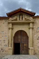 wooden door with stone columns of church of St. Andrew in Rascafria, province de Madrid. Spain