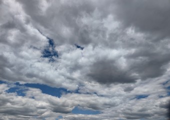 Low dark blue sky and low thunderous white-dark feather clouds.