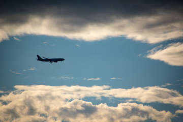 silhouette of airplane flying over cloudy sky