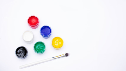 Cans of different colors gouache paints and artist brush, white background, copy space, 16:9
