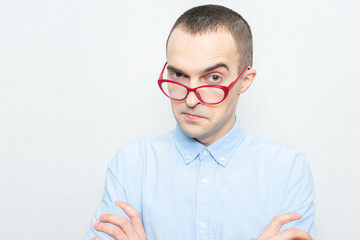 Nerd guy in red glasses looks thoughtfully at the camera, portrait, white background