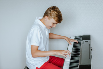 Cute young male teen playing the synthesiser on white background