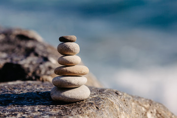 Fototapeta na wymiar Stones pyramid on pebble beach, stability, zen, harmony, balance concept. With blur sea background on a sunny day.