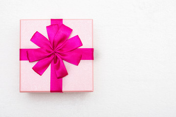 Gift with pink ribbon for Valentine's Day, white background, closeup, copy space, top view
