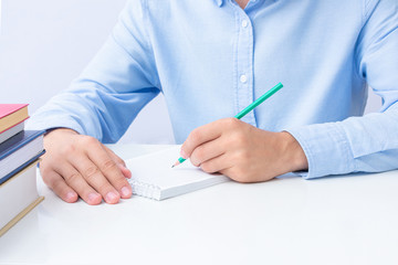 Man writes in a notebook, man's hands with a pencil, close-up