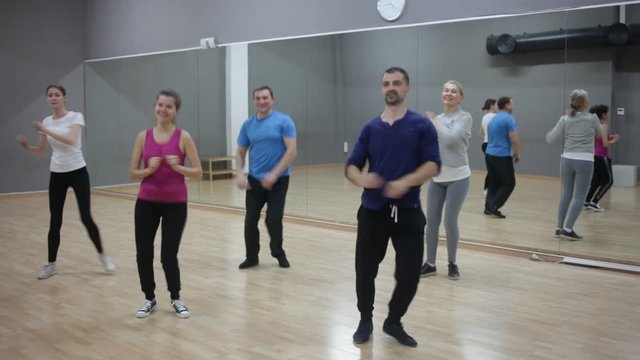 Cheerful people practicing vigorous lindy hop movements in dance class