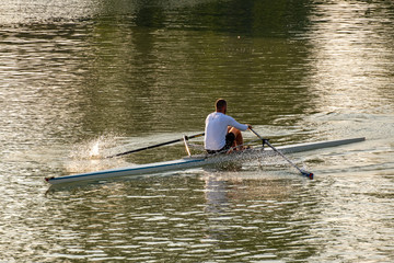 A young male athlete is rowing in a single scull on the Danube, Budapest Hungary © Barnabas