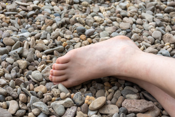 Partial view of a human bare foot on pebbles