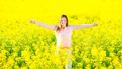 Naklejka na ściany i meble Girl in a blooming rapeseed field, cheerful happiness