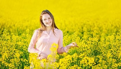 Fototapeta premium Girl in a blooming rapeseed field, cheerful happiness
