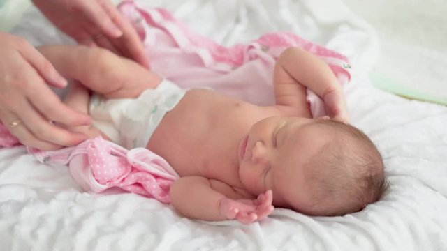 Cute little newborn baby girl sleeping in a dream. Mom gently takes the baby