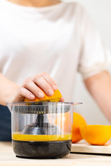 a woman's hand squeezing half an orange in a juicer