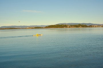 An elderly, silver-headed woman paddle kayak alone  on the Oslo fjord during early spring
