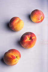 Four delicious yellow and orange peaches on a light colored background. Vertical format. Aerial view.