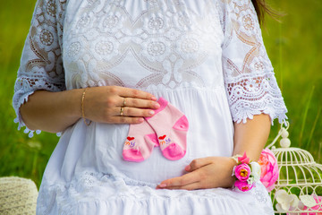 A young pregnant girl in a white lace dress holds small pink socks in her hands.
Motherhood is a wonderful time.
A healthy lifestyle is the health of the unborn child.