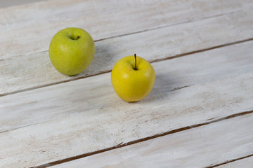 Yellow and green apples on white wooden background