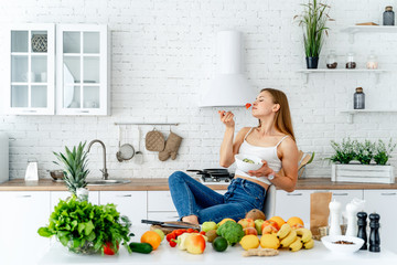 Healthy diet. Beautiful woman eating fresh organic vegetarian salad in modern kitchen. Healthy eating, food and lifestyle concept. Health, beauty, dieting concept.